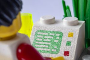 A LEGO man sitting in front of a lego computer screen.